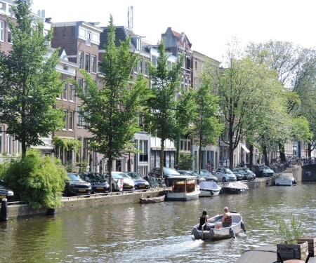 Dos personas navegando en un barco por un canal de Amsterdam.