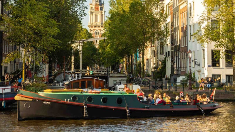 Barco clásico al atardecer en los canales de Ámsterdam con un grupo